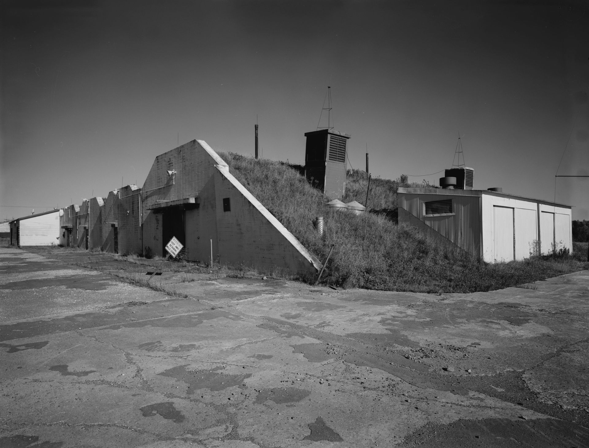 The earthen-mound-covered retaining wall of Building 216, an ammunition maintenance shop in the nuclear Weapons Storage Area (WSA) at Loring Air Force Base, Limestone, Maine, photographed for the Historic American Engineering Record