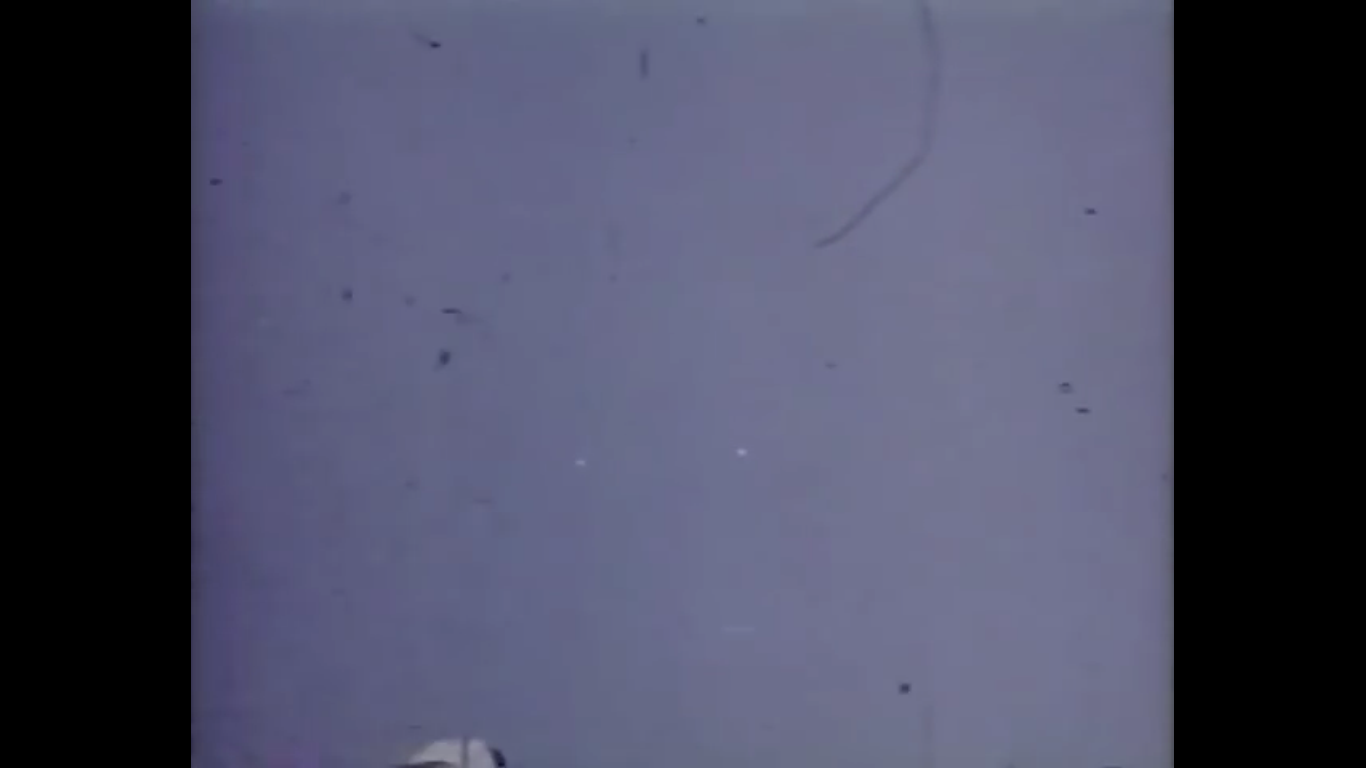 A surviving frame from Nick Mariana's 16mm color film of two unidentified objects over Great Falls, Montana, August 15, 1950 — the two bright points of light are visible against the sky, with age-related scratches on the original film stock