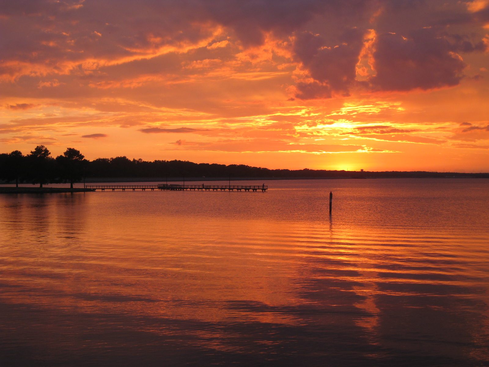 Sunset over Ross Barnett Reservoir near Ridgeland, Mississippi, looking out from the shoreline toward the public fishing pier — the setting of the founder's 2012 sighting